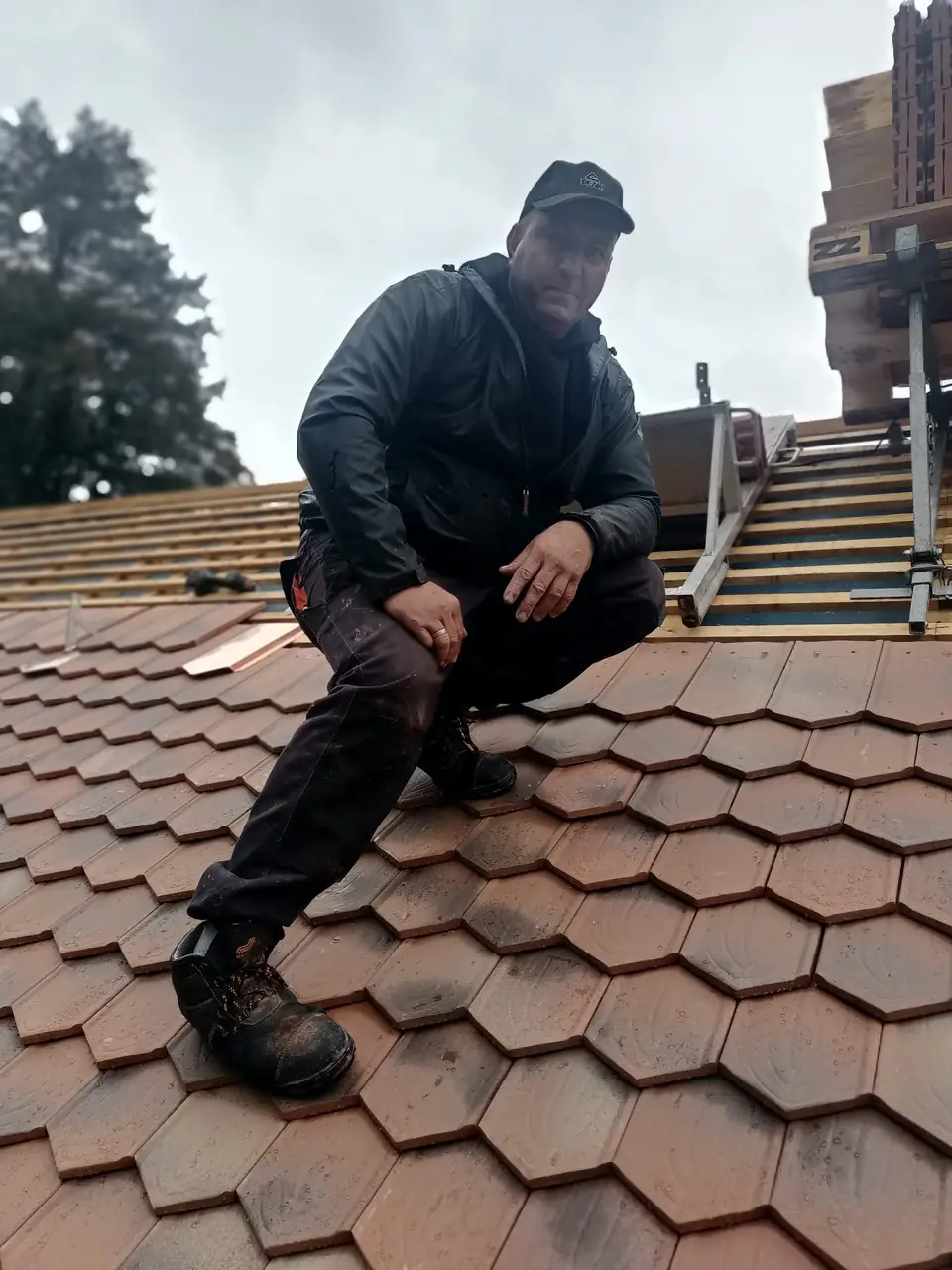 Dekarz przy pracy na dachu krytym dachówką ceramiczną