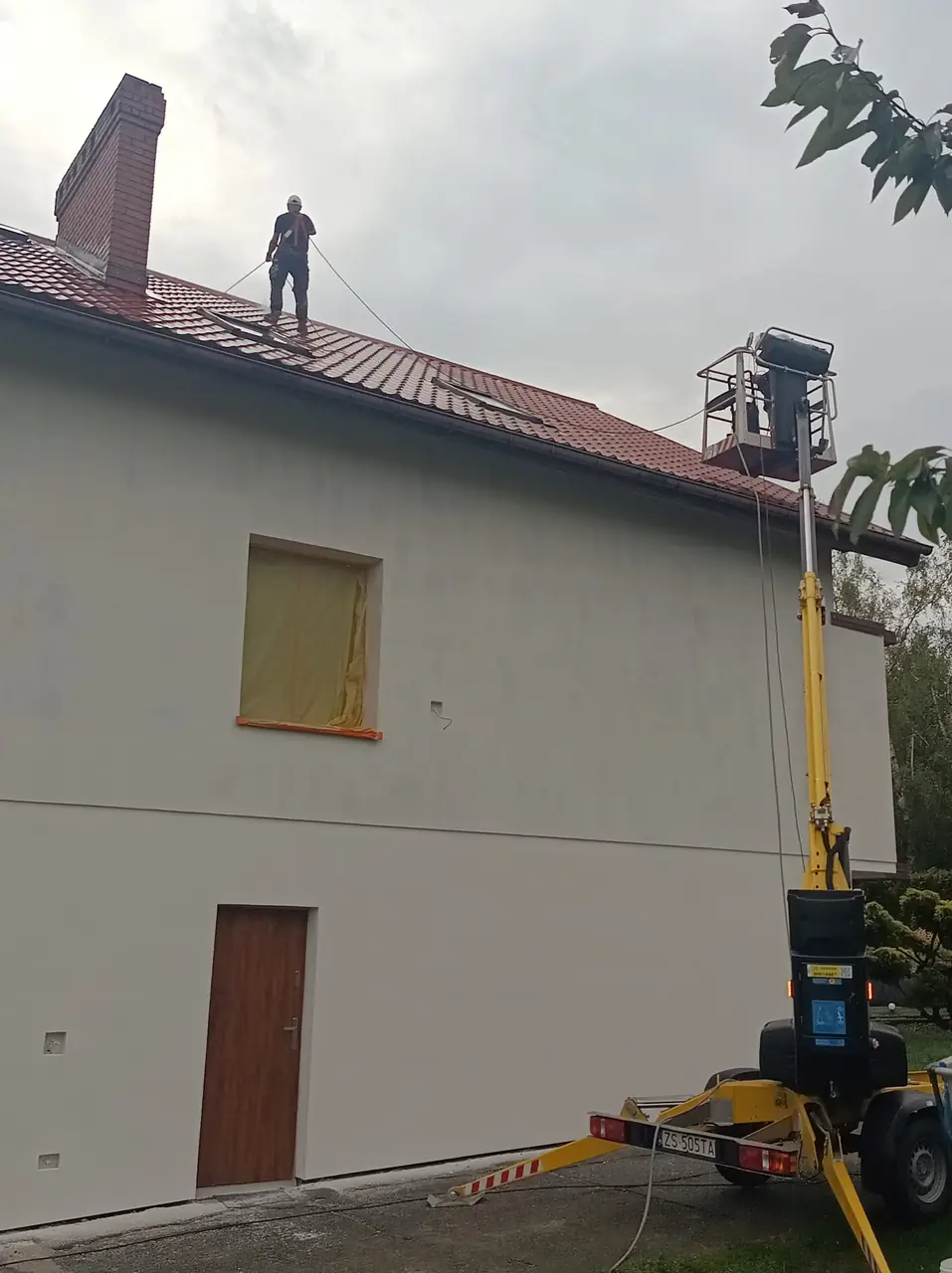 Podnośnik koszowy przy elewacji i dachu podczas prac wysokościowych
